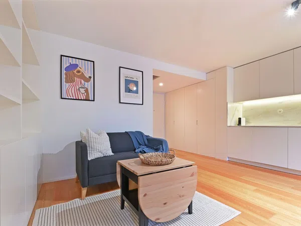 Moderna sala de estar no Apartamento T1 em Matosinhos, com móveis elegantes, cozinha em plano aberto e janelas amplas que proporcionam muita luz natural